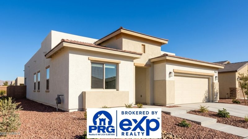 Modern beige stucco house with a tiled roof, garage, and desert landscaping under a clear blue sky.