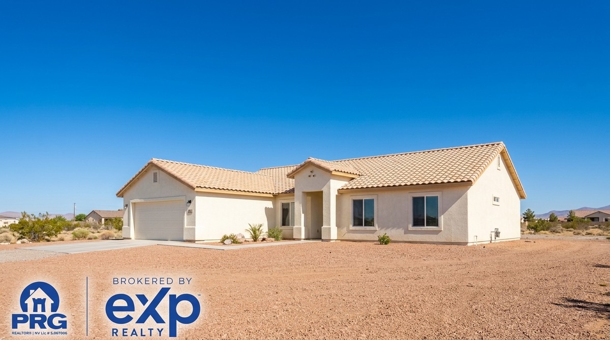 A beige stucco house with a tiled roof and attached garage sits on a gravel lot under a clear blue sky.