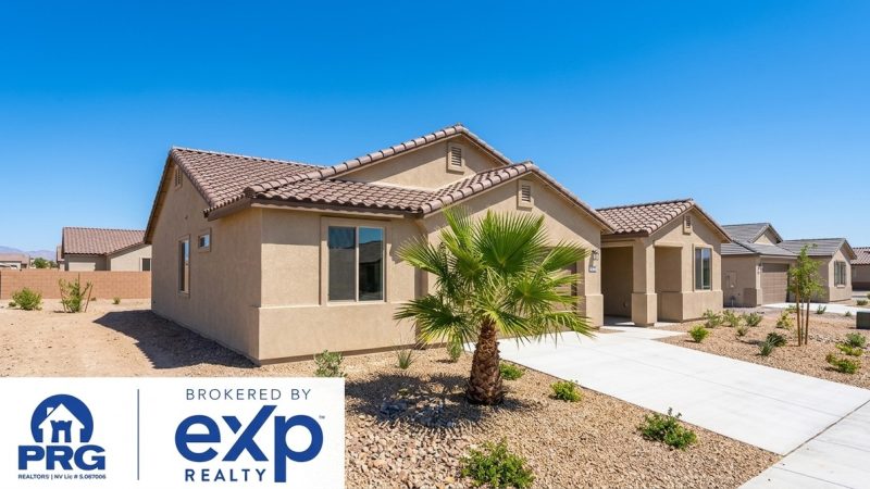 A row of new construction homes with tan stucco, tile roofs, and desert landscaping under a clear sky.